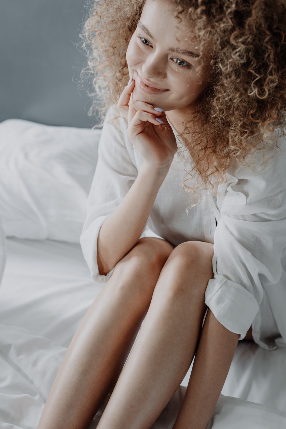 Une femme souriante assise sur un lit